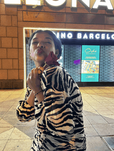 a woman blowing a kiss in front of a sign for ode restaurant