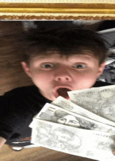 a boy is holding a bunch of money in front of his mouth
