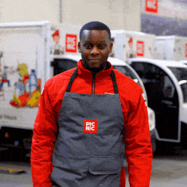 a man wearing a red jacket and a gray apron that says pic nic