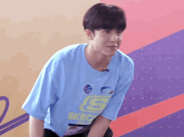 a young man wearing a blue shirt that says skechers