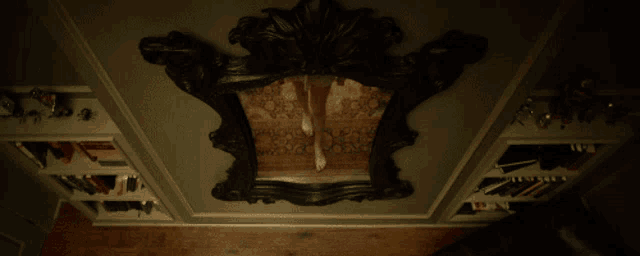 a woman looking at her reflection in a mirror with a bookshelf behind her
