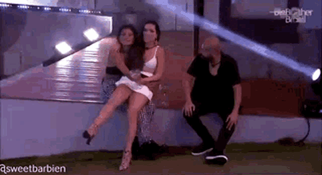 a woman in a white dress is sitting on a man 's lap while a man sits next to her .