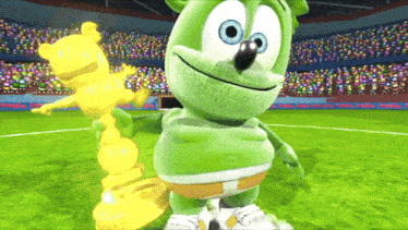 a gummy bear is holding a gold trophy in a stadium