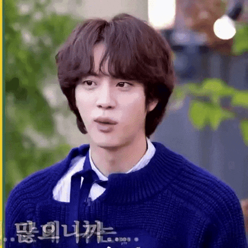 a man wearing a blue sweater and tie is making a funny face .