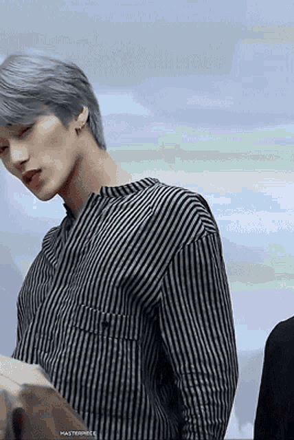 a man with gray hair is wearing a black and white striped shirt
