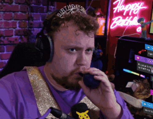 a man wearing headphones and a birthday tiara is talking into a microphone