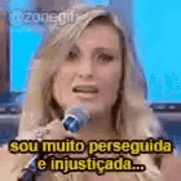 a woman is talking into a microphone and saying `` sou muito perseguida e injusticada '' .