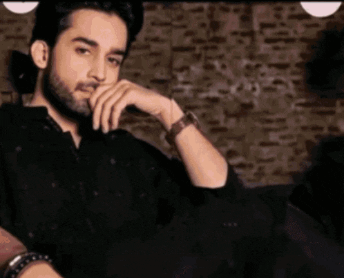 a man with a beard is wearing a watch and a bracelet on his wrist