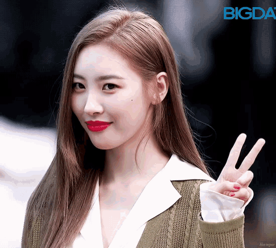 a woman with red lipstick is giving a peace sign