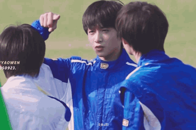 a boy wearing a blue omp jacket is pointing