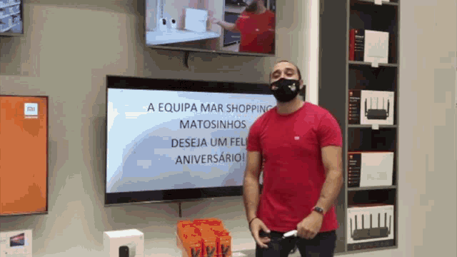 a man wearing a mask stands in front of a screen that says a equipe mar shopping matosinhos