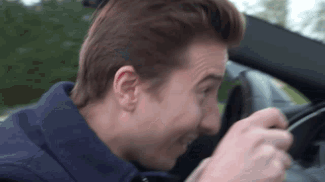a man in a blue jacket is sitting in a car