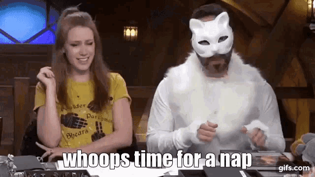 a man in a cat mask is sitting next to a woman in a yellow t-shirt .
