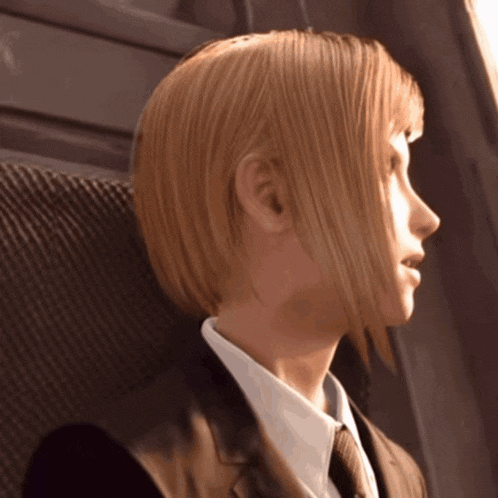 a woman with blonde hair and a suit and tie looks to the side