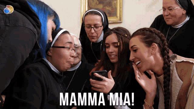 a group of women looking at a cell phone with the words mamma mia written on the bottom