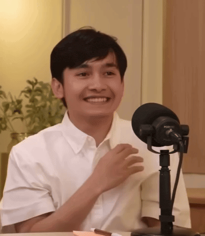 a man in a white shirt is smiling in front of a rode microphone .