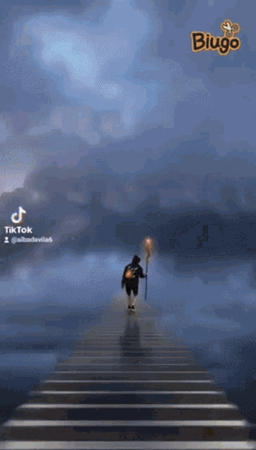 a person walking on a bridge with a torch in their hand and the word biugo in the corner