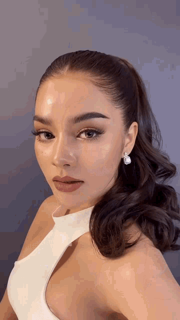 a close up of a woman 's face with a ponytail and earrings