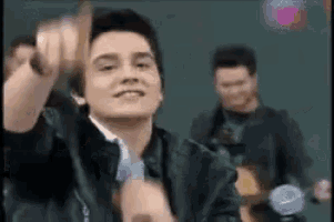 a man in a leather jacket is holding a microphone and making a funny face