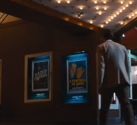 a man in a suit stands in front of two posters one of which says radio patrol