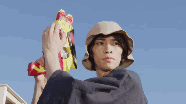 a man in a hat holds a toy gun in his hand