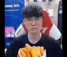 a man wearing glasses is holding a bag of french fries in front of his face .