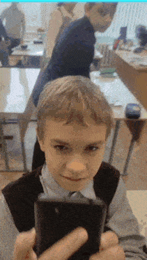 a young boy is taking a picture of himself in a classroom with his phone