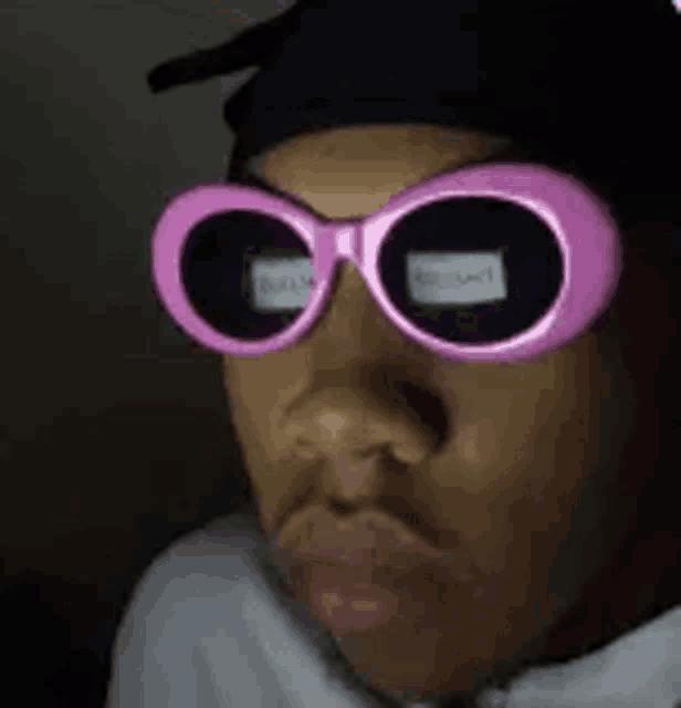 a close up of a person wearing pink sunglasses and a hat .
