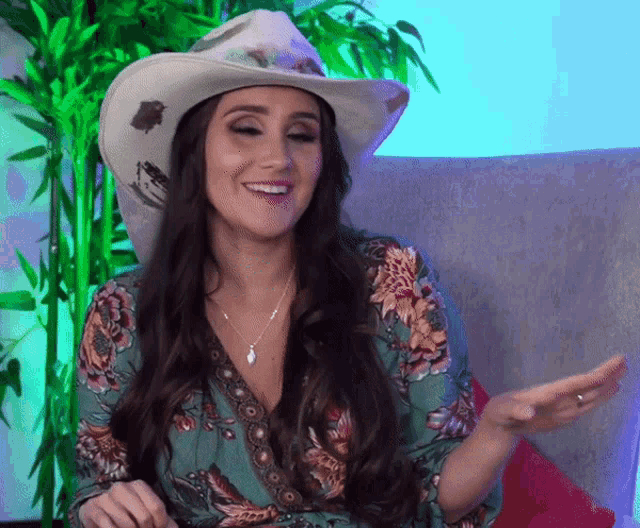 a woman is wearing a cowboy hat and a floral dress
