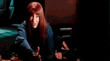 a woman with red hair is sitting at a table holding a bottle of alcohol .