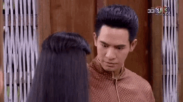a man and a woman are looking at each other in front of a wooden wall .