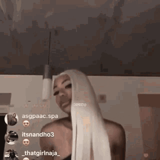 a woman with long white hair is standing in front of a ceiling in a room .