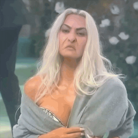 a woman with long white hair is wearing a sweater over her shoulder and a bra .