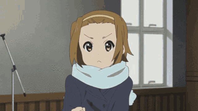 a girl with a scarf around her neck looks angry in front of a window
