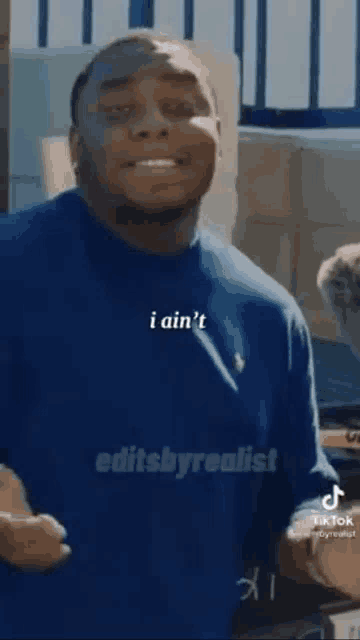 a man in a blue shirt is making a funny face while standing in a room .