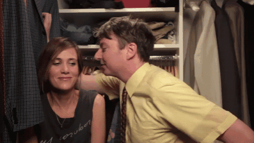 a man in a yellow shirt kisses a woman in a black shirt that says " my computer "