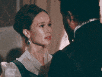 a man and a woman are looking at each other and the woman has a crown on her head