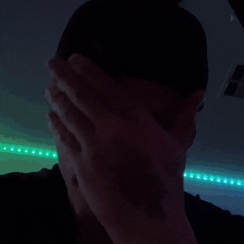a person covering their face with their hand in the dark