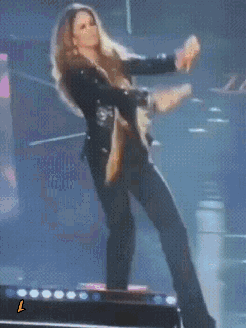 a woman in a black jacket is dancing on a stage with the letter l next to her