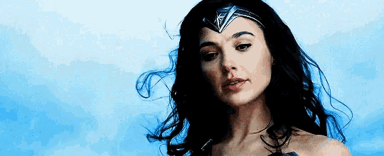 a woman in a wonder woman costume with her hair blowing in the wind .