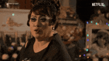 a woman is wearing a tiara and earrings while standing in front of a netflix sign .