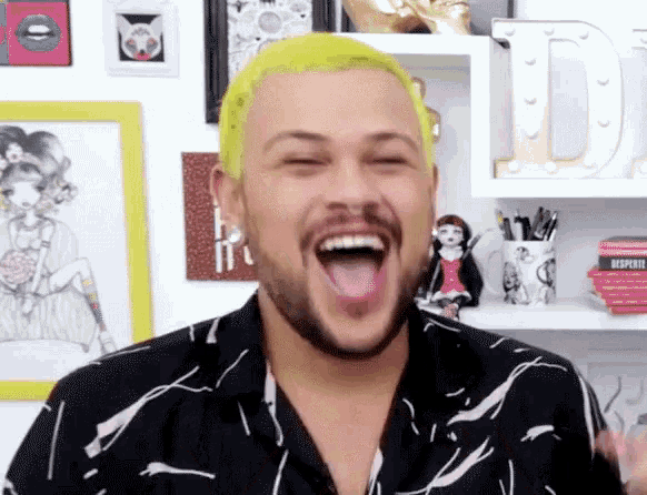 a man with yellow hair and a beard is laughing with his mouth wide open