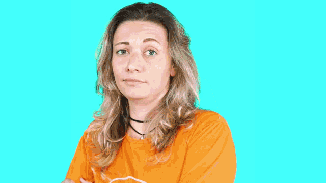 a woman wearing a choker and an orange shirt makes a face