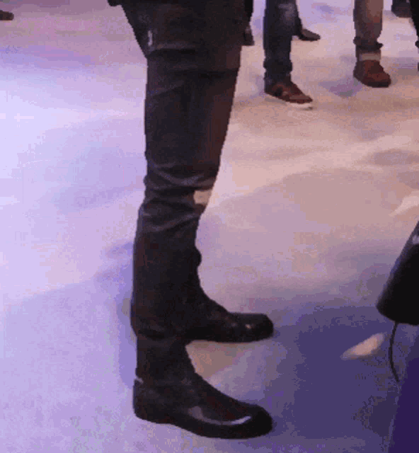 a person wearing a pair of black boots standing on a blue floor
