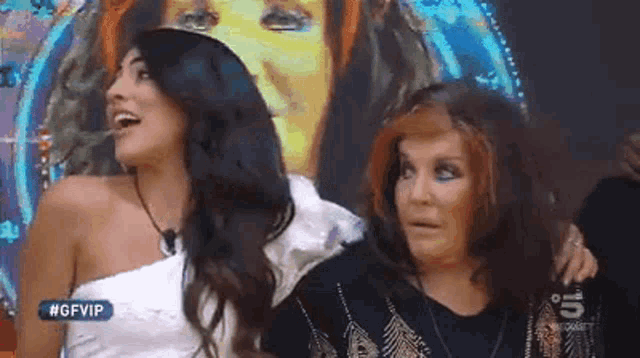 two women are standing next to each other in front of a painting that says #gfvip on it