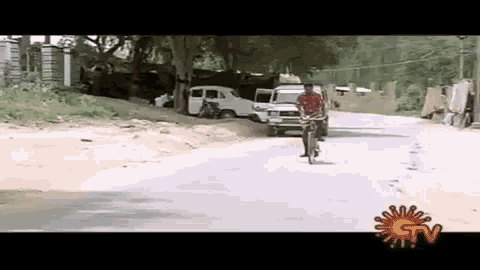 a man is riding a bicycle down a road next to a car .