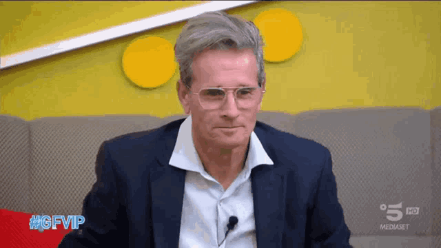a man wearing glasses and a suit is sitting in front of a screen that says gfvip