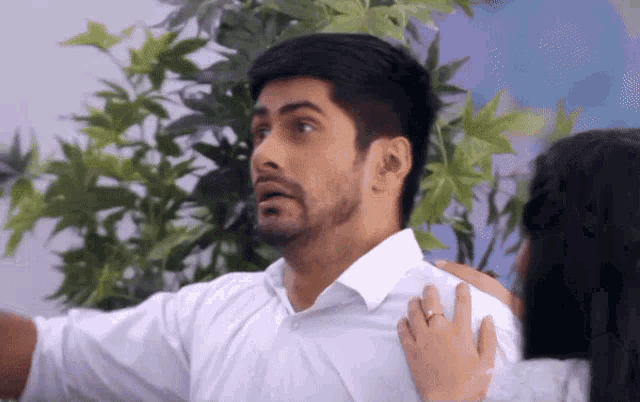 a man in a white shirt is being held by a woman with a ring on her finger