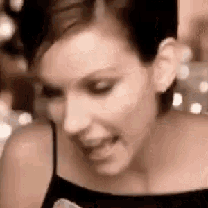 a close up of a woman 's face with her tongue out and a black tank top .