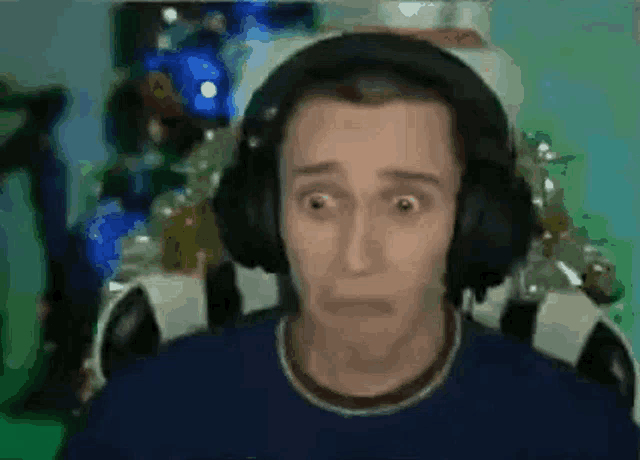a man wearing headphones is making a funny face while sitting in front of a green screen .